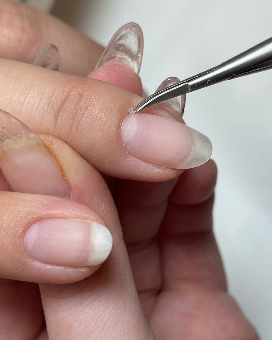 Close-up of an electric nail drill bit removing dead skin around the cuticle area.