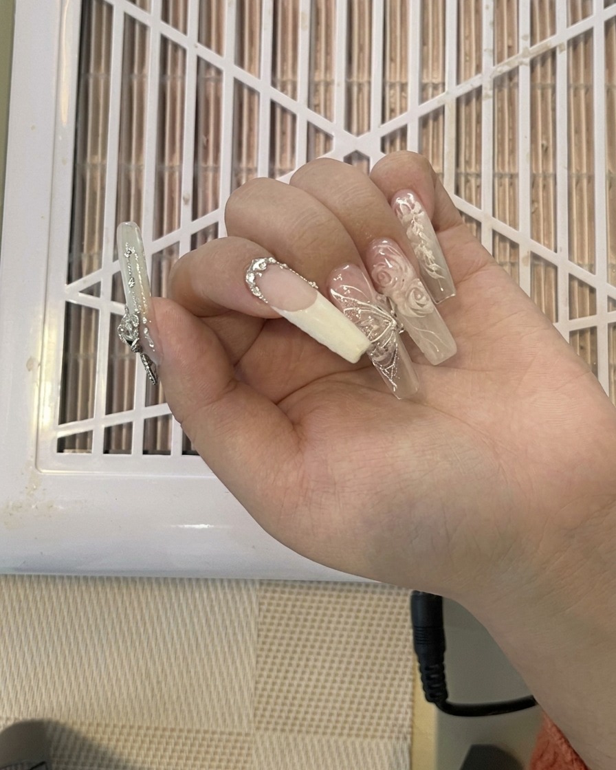 A pair of nail clippers cutting off a long, decorated nail extension.