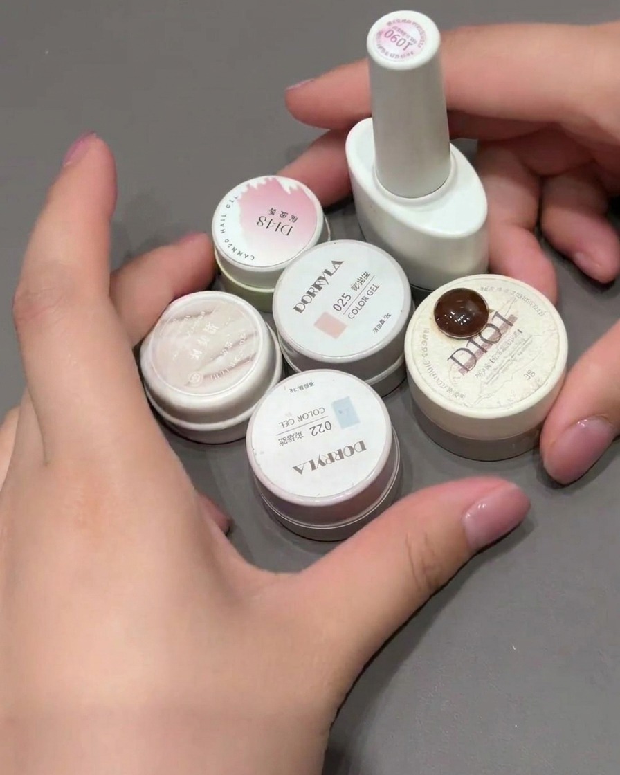A makeup sponge being dabbed onto a nail tip to create a pink gradient fade.