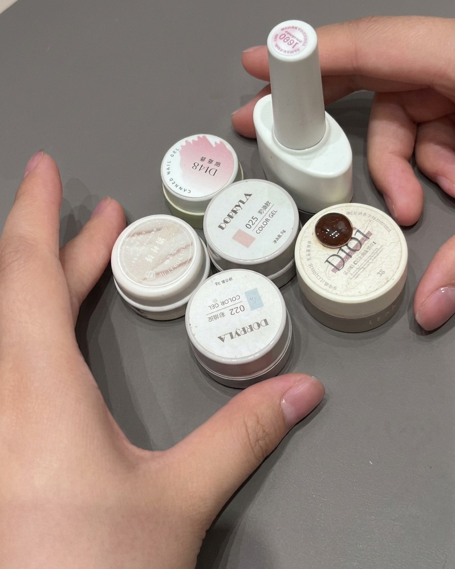A final layer of glossy top coat being applied over a pink gradient French nail.