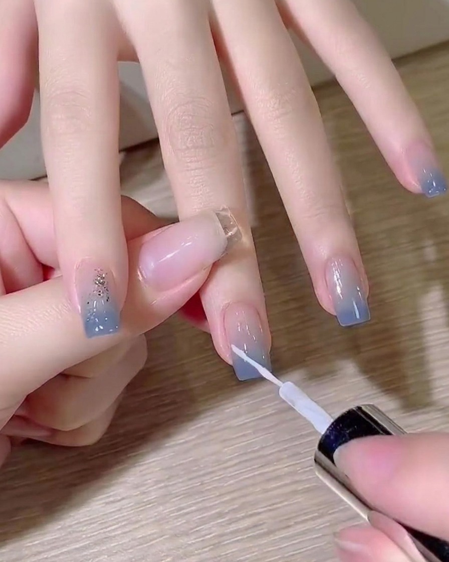 A fine liner brush drawing a thin white diagonal line on a gradient nail.