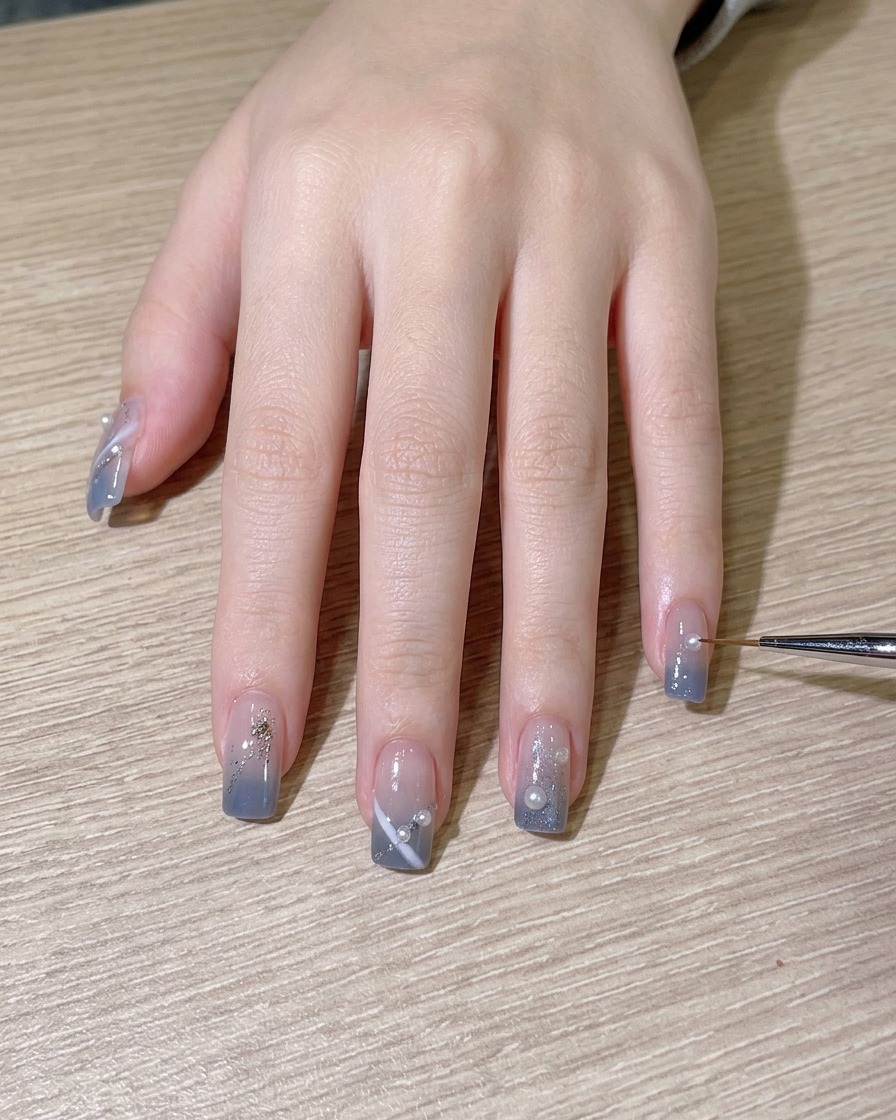 A brush applying a final glossy top coat over the completed nail design.