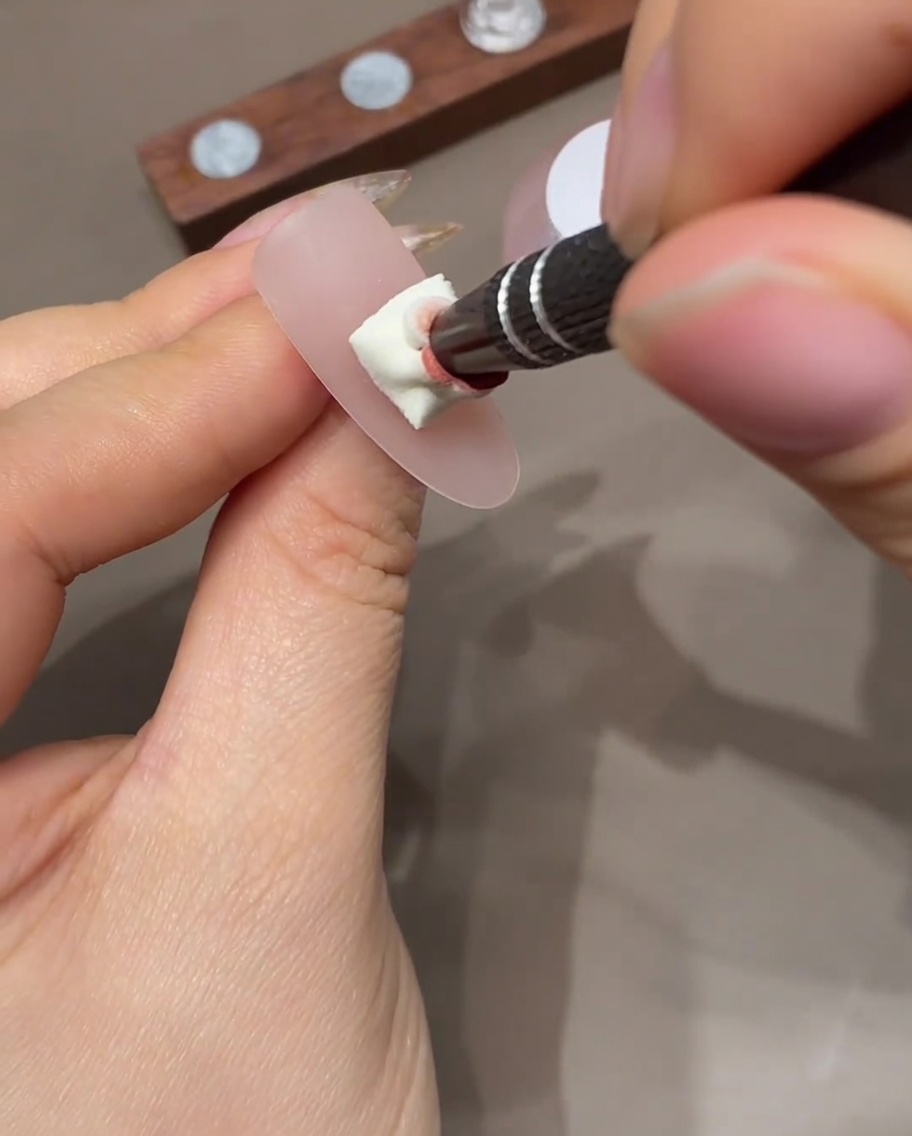 A nail with an ombre effect being cured inside a professional UV nail lamp.