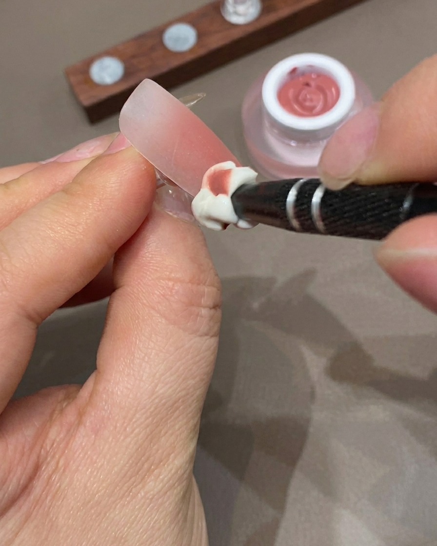 A hand resting inside a UV lamp for curing the ombre nail design.
