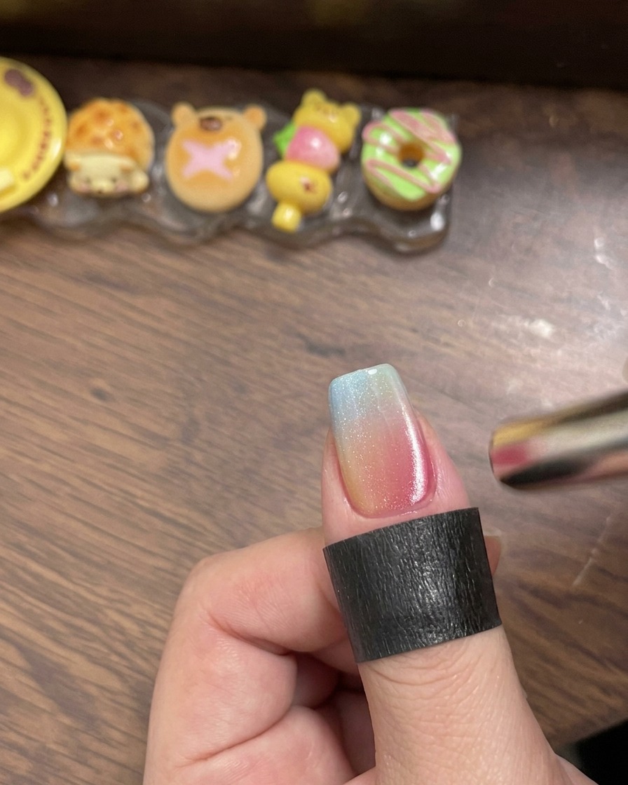 A brush applying clear glossy top coat over the multicolored gradient nail.