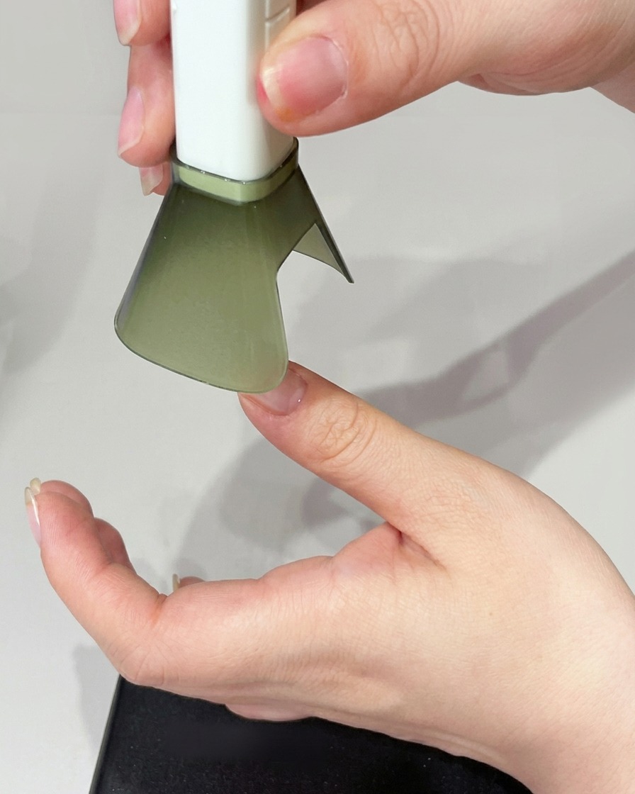 A hand positioned under a UV lamp, curing the nail.