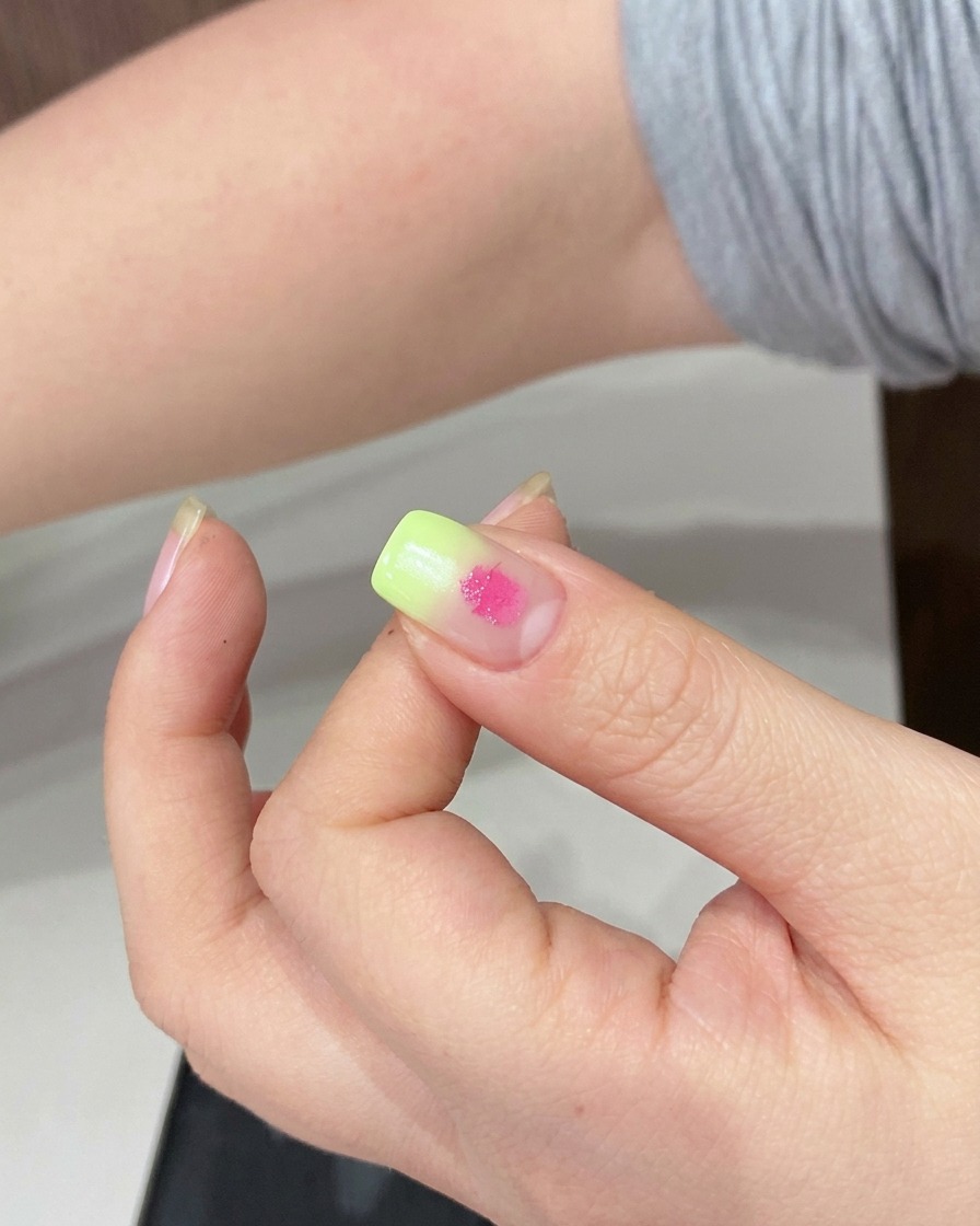 A sponge being used to blend the pink gel dot on the nail surface.