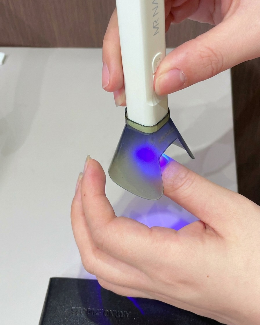 A brush applying a layer of clear cat eye gel over the entire surface of the nail.