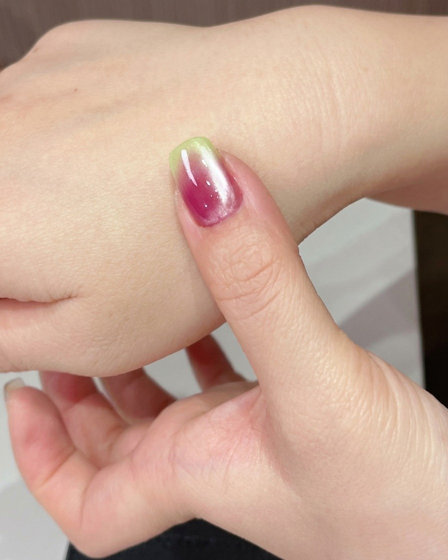 A hand positioned under a UV lamp to cure the freshly applied cat eye gel.