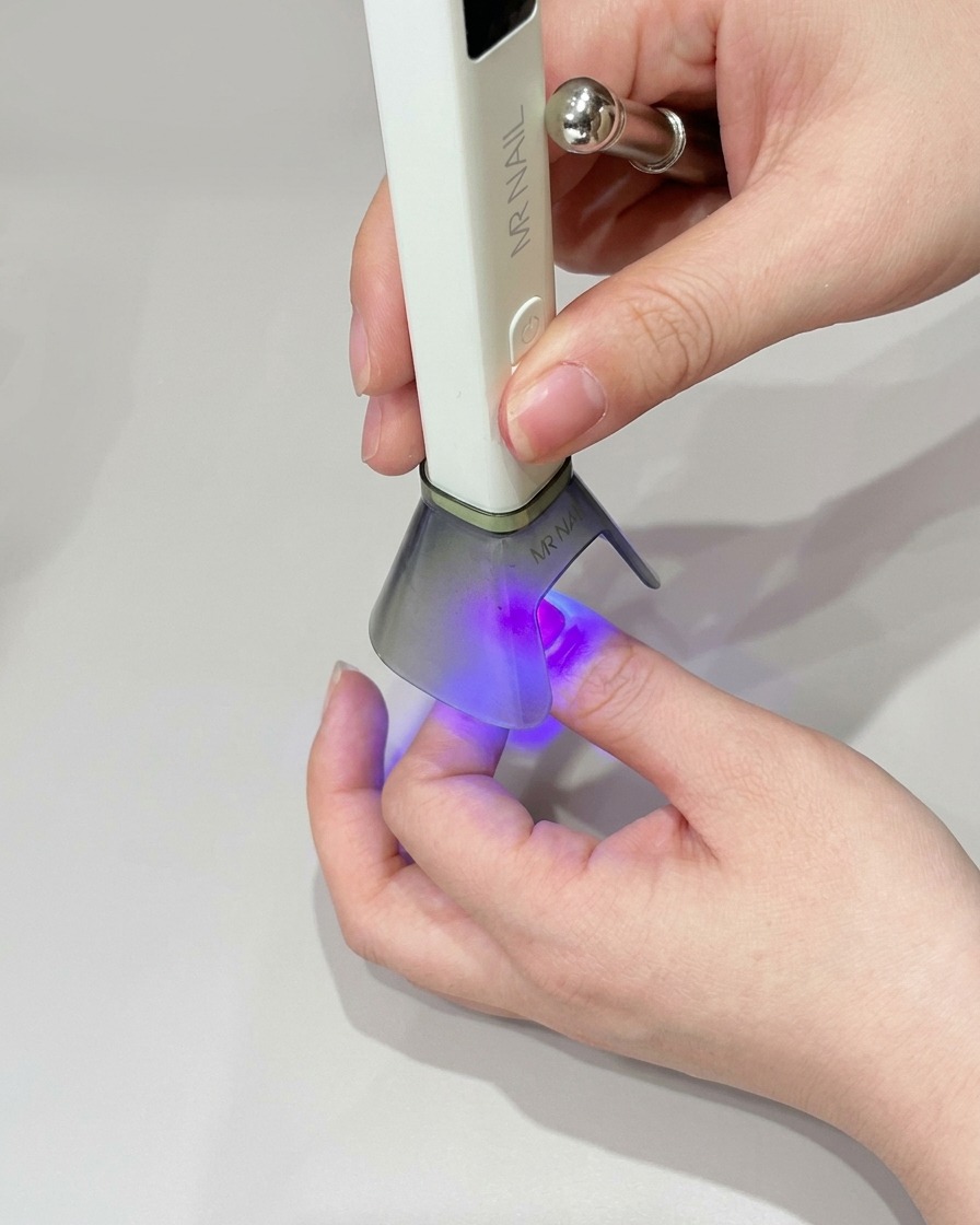 A small makeup sponge applying green gel polish to the tip of the nail to deepen the color.