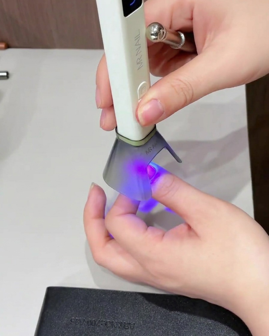 A brush applying a shiny top coat over the entire surface of the nail.