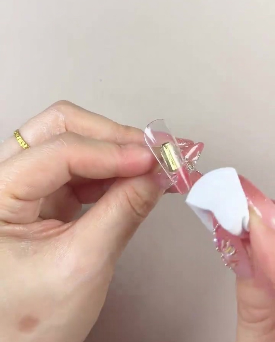 A makeup sponge moving left and right over the nail to blend the gel color.