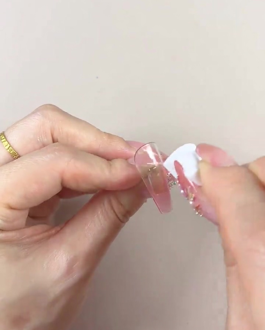 A hand using a clean section of a cosmetic sponge to smooth and refine the color gradient on a nail tip.