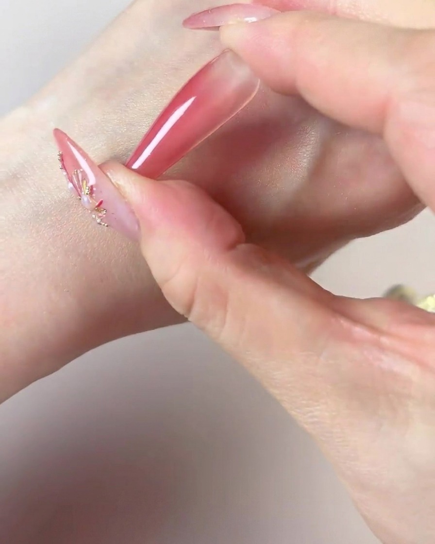 A hand using the dark center of a makeup sponge to add concentrated color to the tip of a long nail.