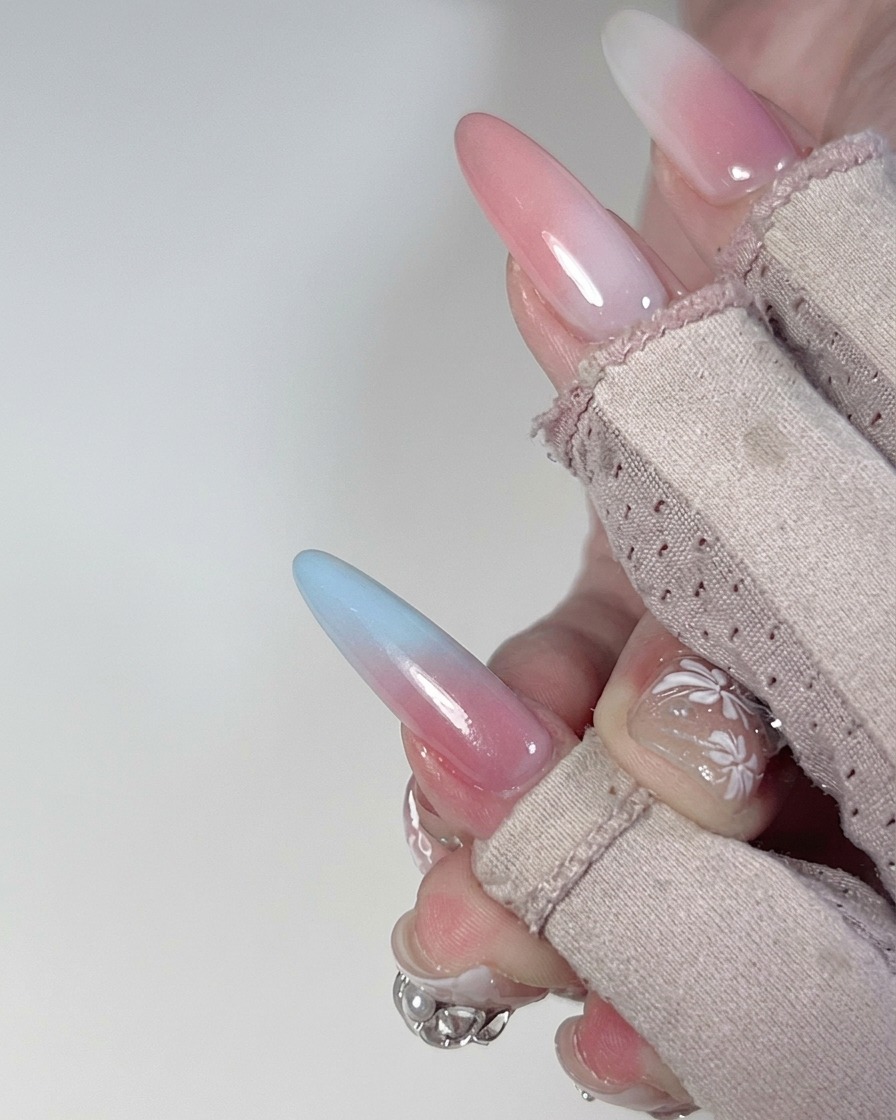 A close-up of a sponge blending the blue and pink transition zone on a fingernail.