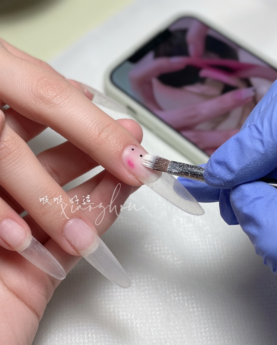 A nail brush spreading a soft nude gel polish across the nail plate.