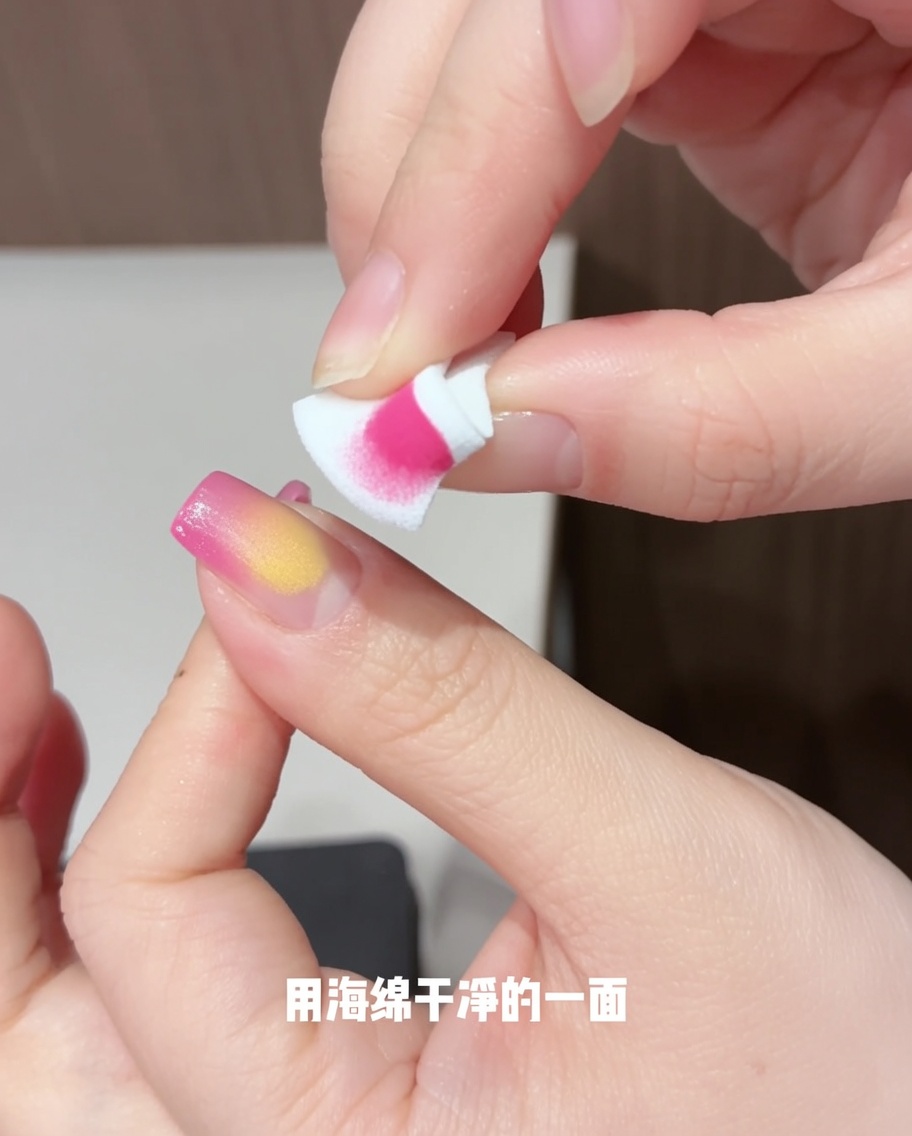 A sponge being used to carefully tap and spread yellow gel over the nail to create a petal-like blended shape.