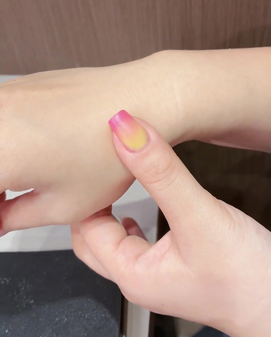 A fingernail with the completed tulip design being cured under a UV/LED lamp.