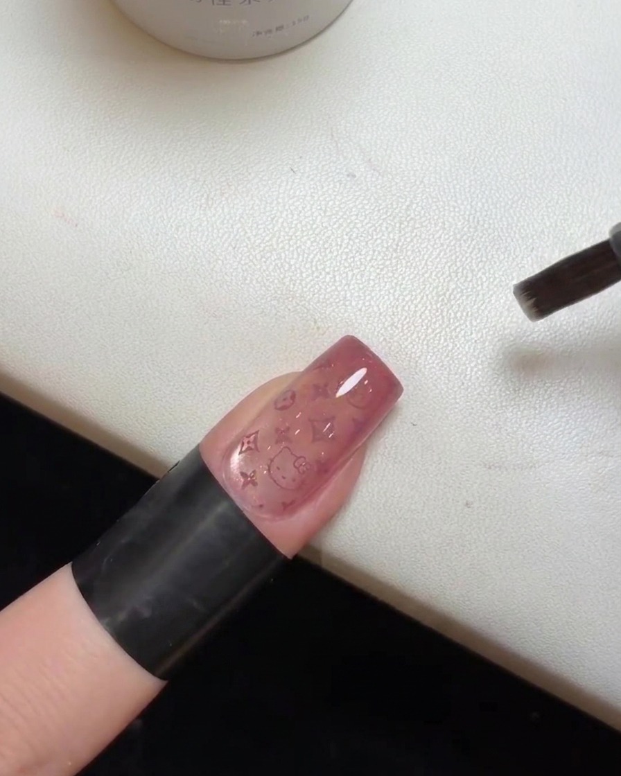 A close-up of a finished nail with the top coat being cured under a UV lamp.