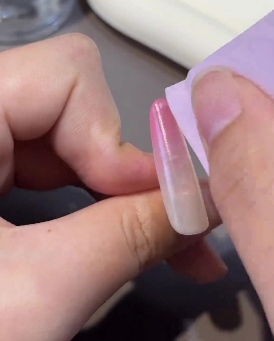 A lint-free wipe cleaning the surface of a cured nail, leaving it clean and ready for further application.