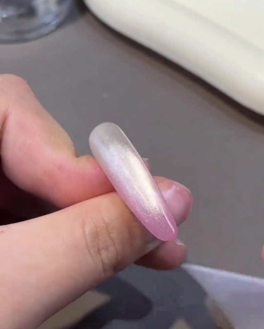 A magnet being held near a nail to manipulate the particles in the wet cat-eye gel.