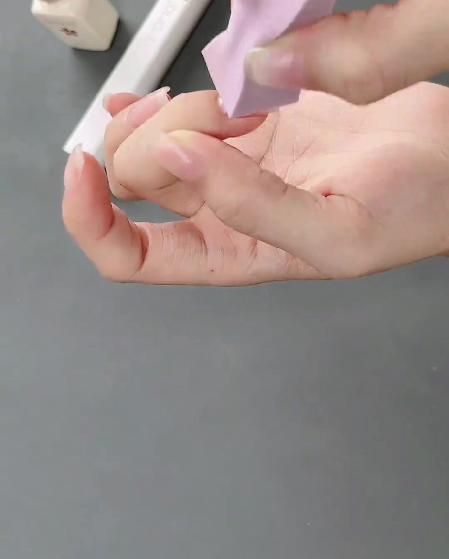 A makeup sponge applying white gel onto a natural fingernail to create a soft gradient effect.