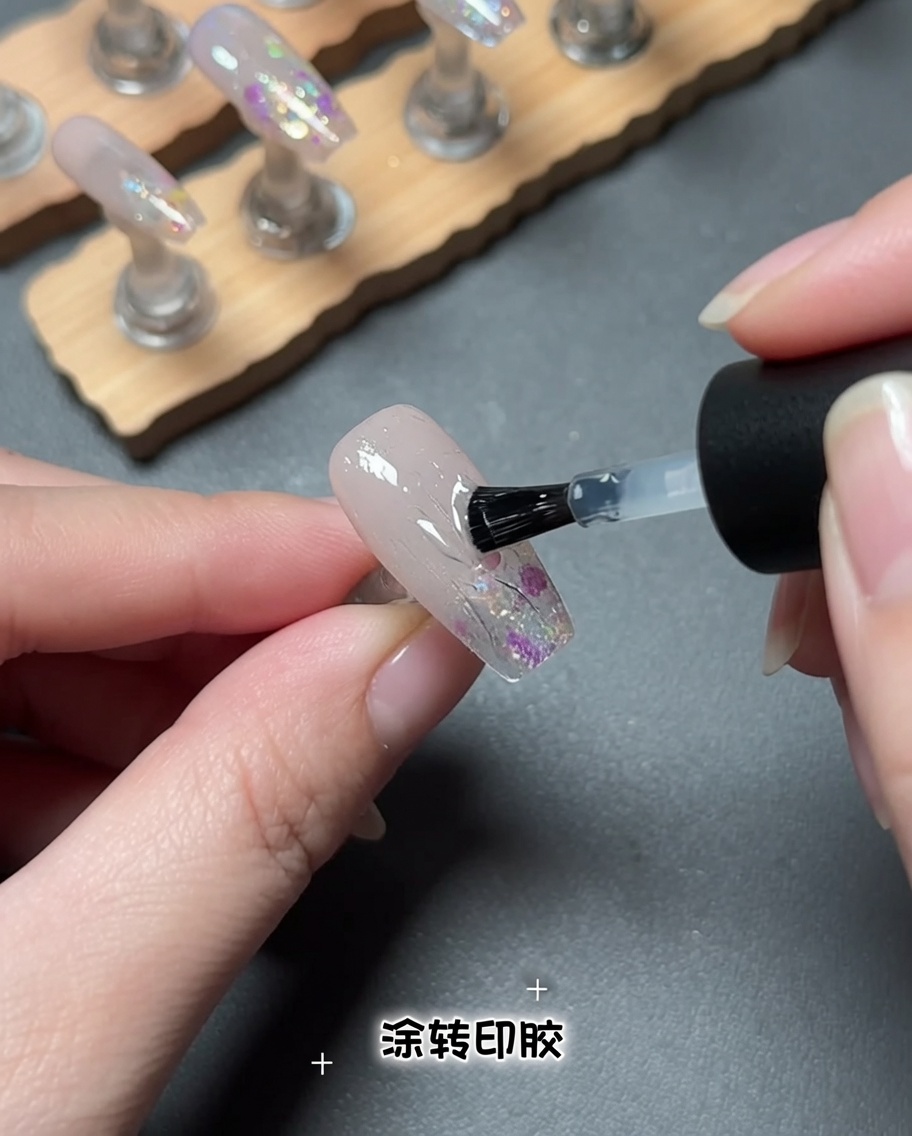 A brush applying a clear gel product to a nail surface.
