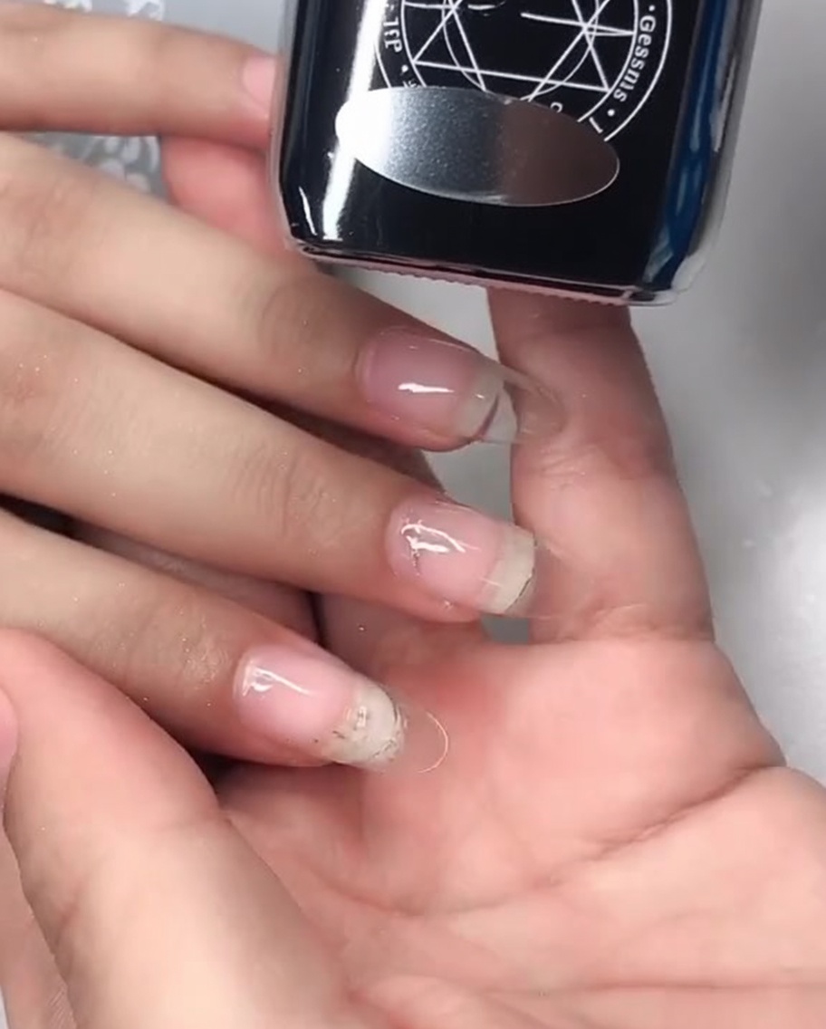 A close-up showing a mirror top coat gel being applied onto the nail surface.