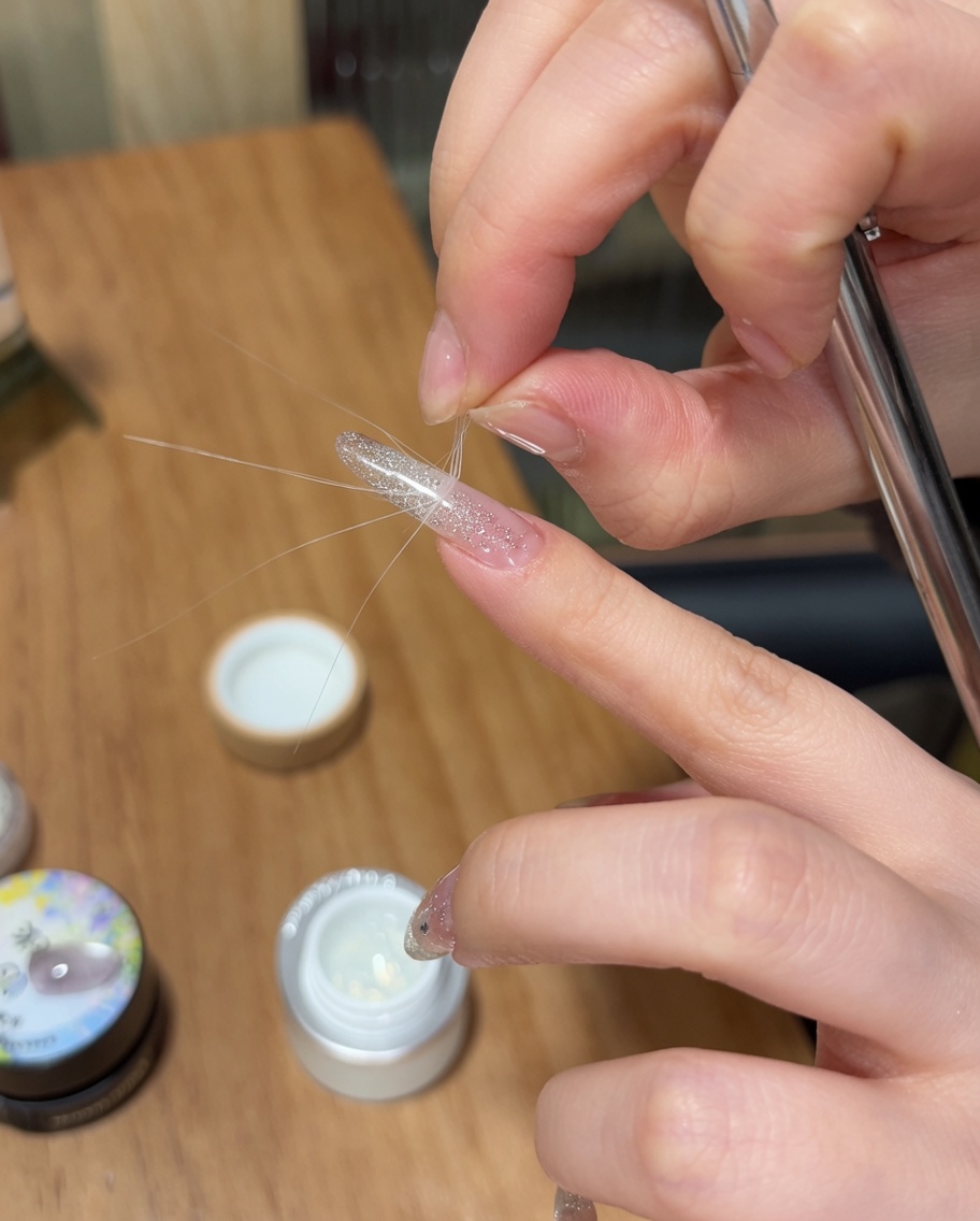 Tweezers peeling a French sticker guide away from the nail, leaving a defined tip area.