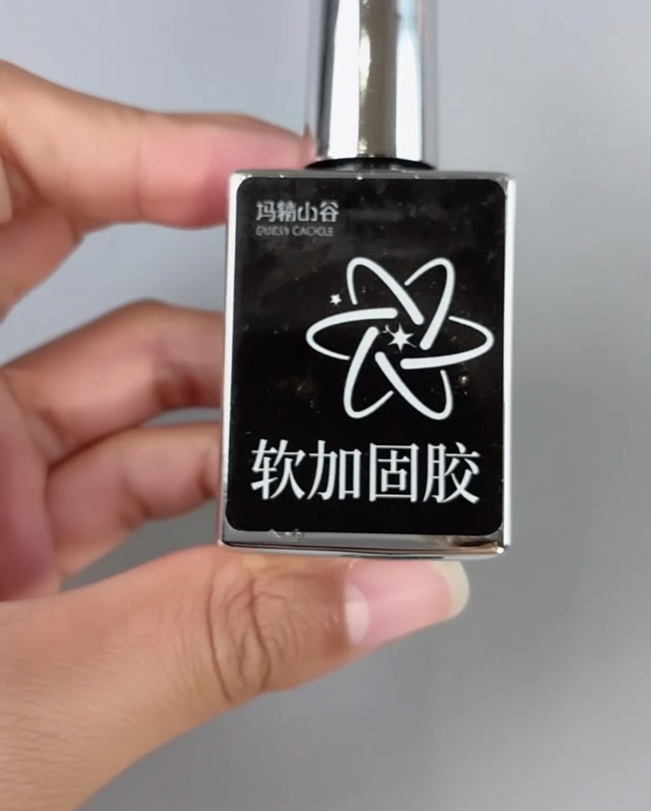 A brush applying clear soft adhesive to the front edge of a nail tip.