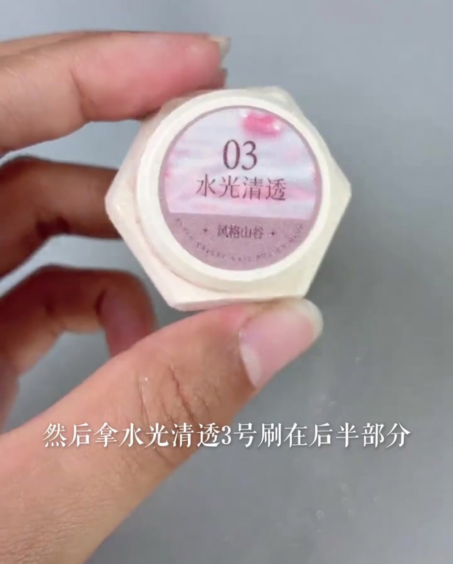 Applying a sheer, glossy pink gel polish over the base area of the nail tip.
