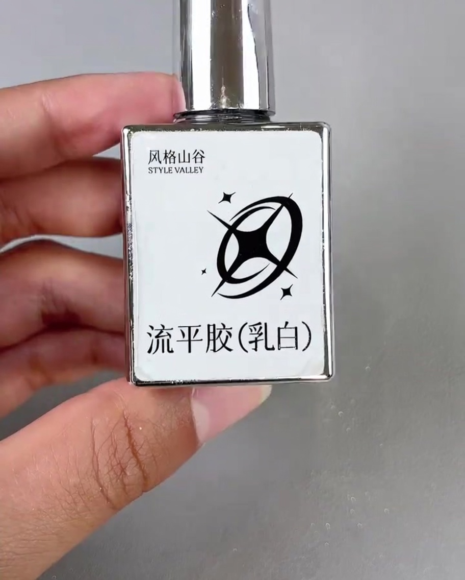 A small brush applying a drop of milky white gel to the corner of a decorated nail.