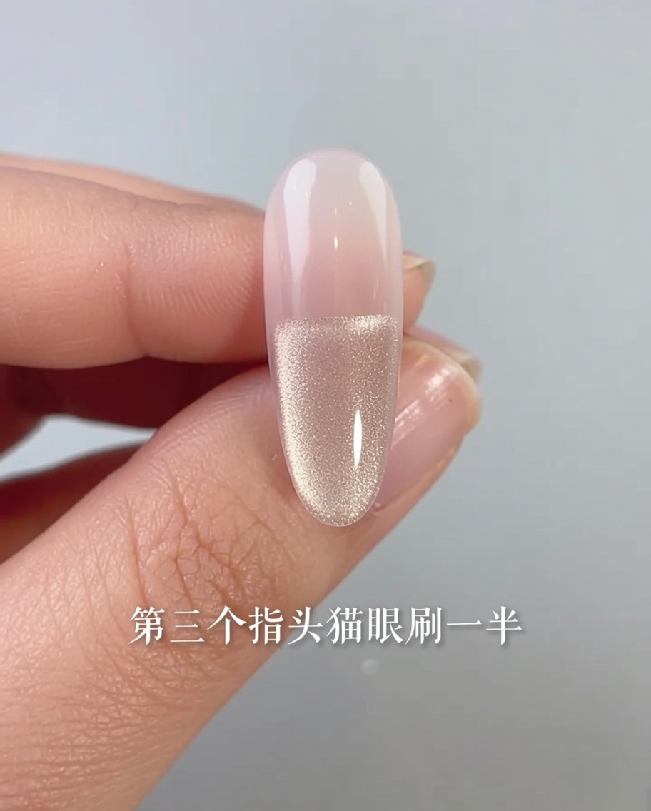 A close-up of a fingernail with a cat-eye gel polish applied only to the bottom half of the nail bed.