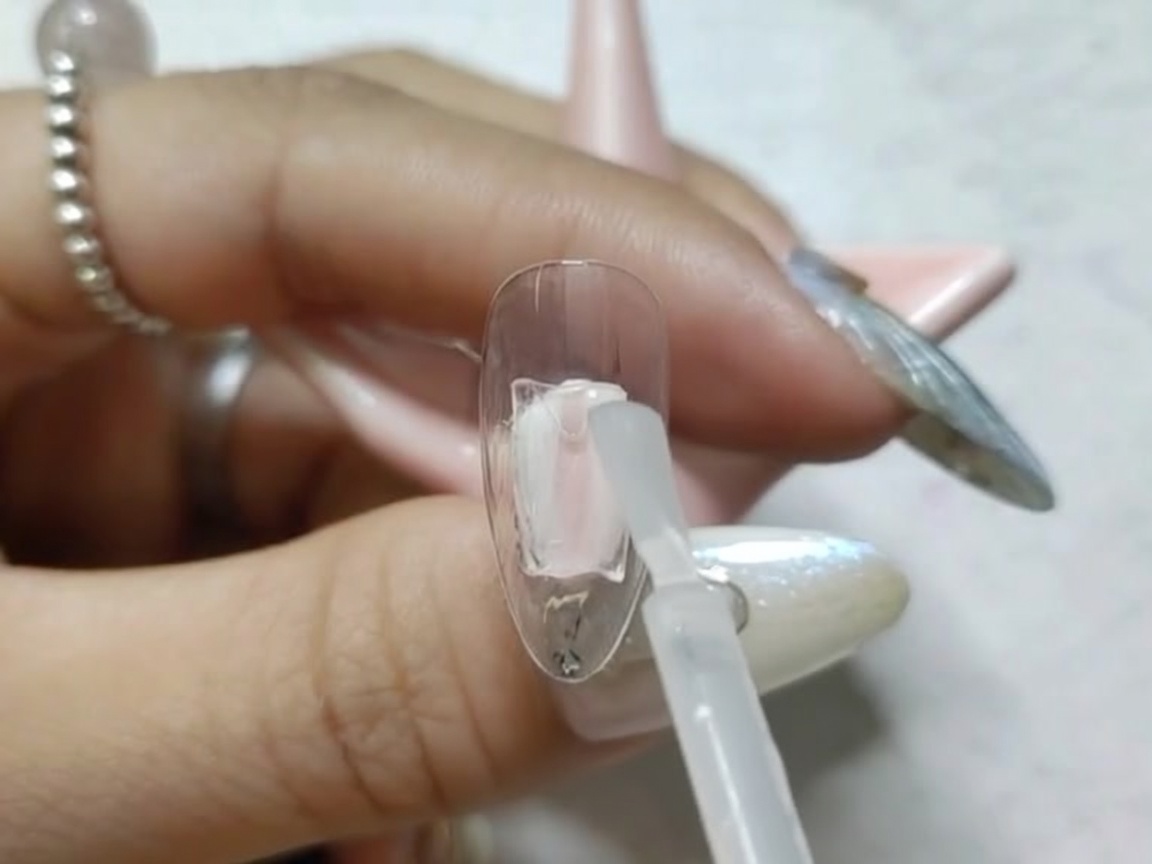 A nail tip placed inside a small UV/LED lamp for curing.