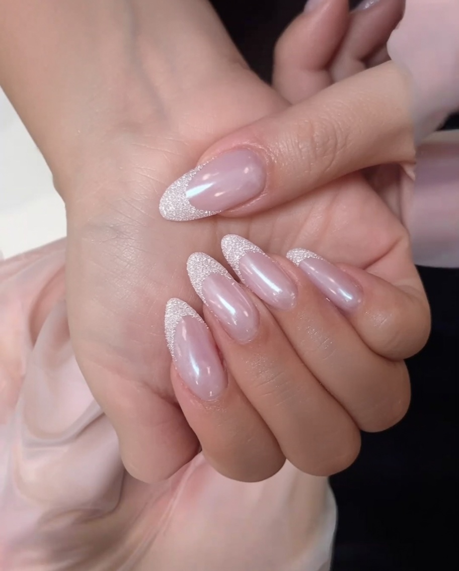 A lint free wipe cleaning the surface of a matte nude pink nail.