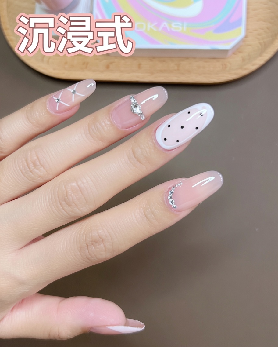 A fine detail brush drawing white crossed lines on a nude-base pinky nail.