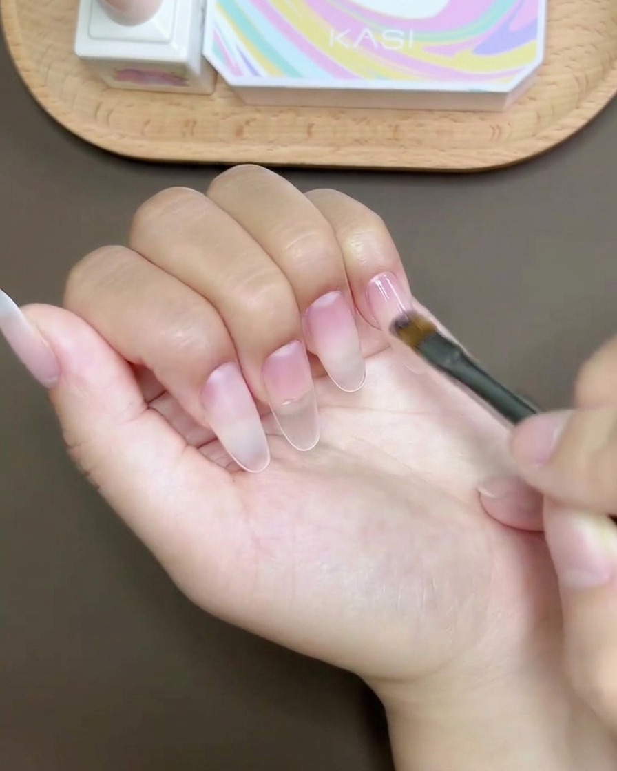 A gel brush applying a smooth, glossy top coat over a finished nail design.