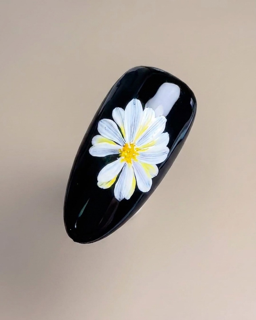 A fine liner brush delicately applying thin yellow and orange lines in the center of the flower.