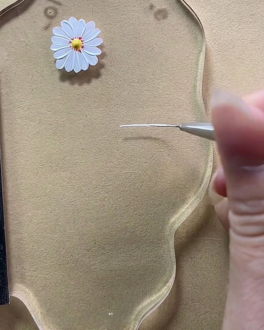 A close-up view of a fine liner brush drawing a single short white vertical line on a transparent palette.