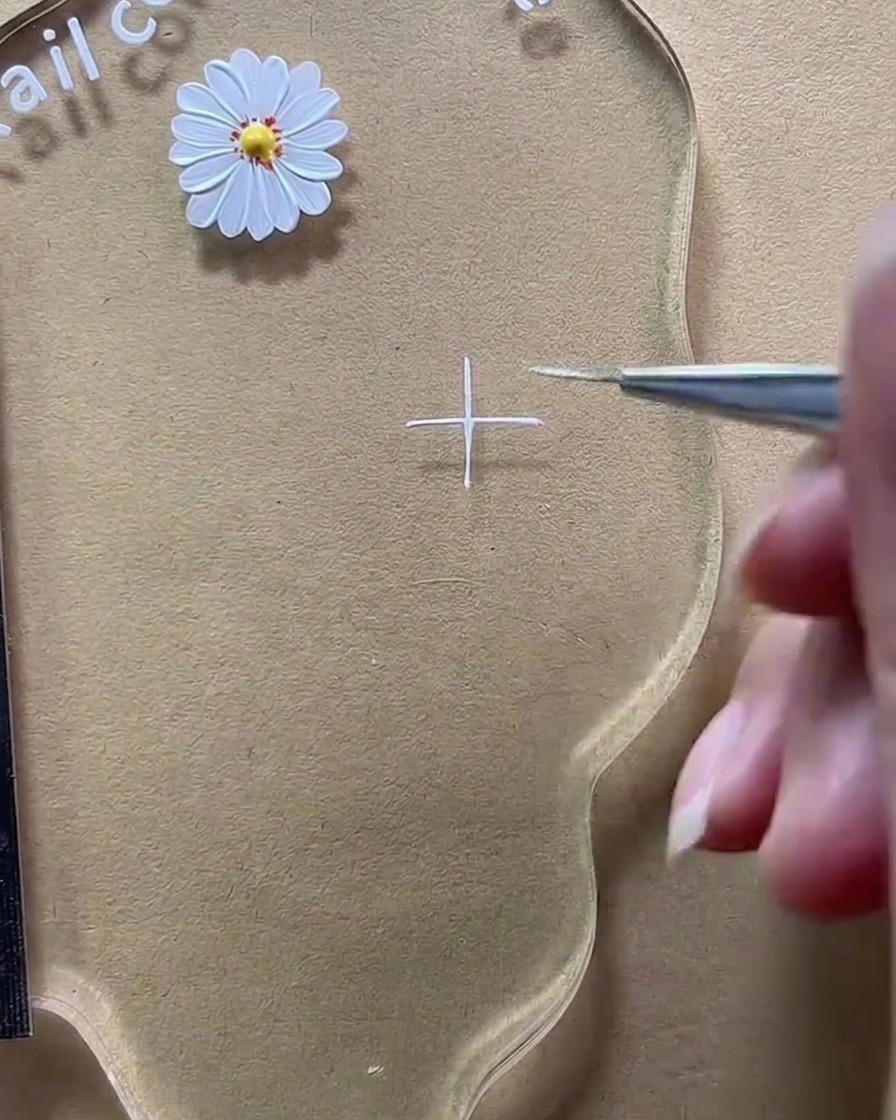 A close-up of a liner brush completing a white plus sign on the clear palette.