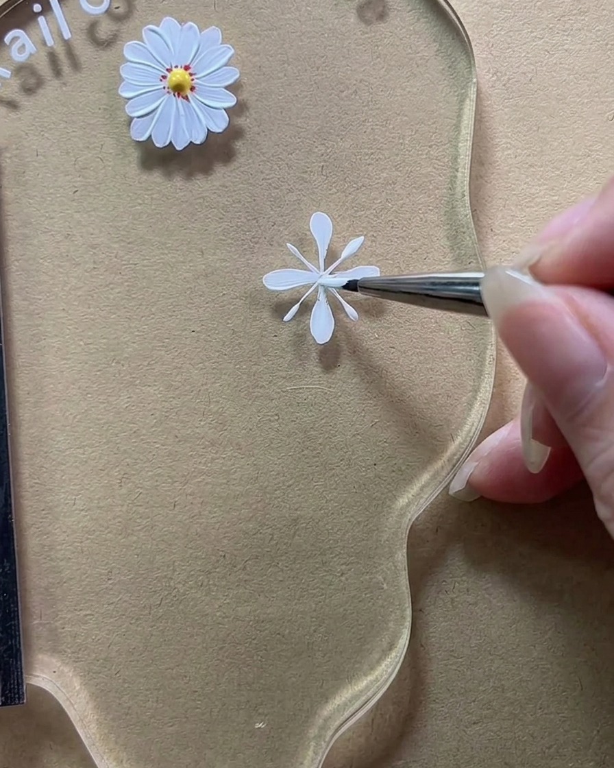A close-up of a brush filling in the vertical guide lines to create full, opaque white petals.