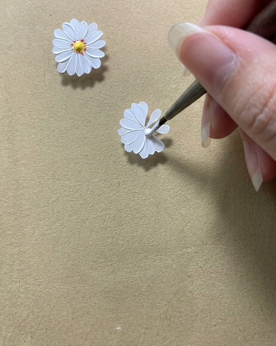 A detail brush perfecting the inner edges of white daisy petals to create a circular space in the middle.