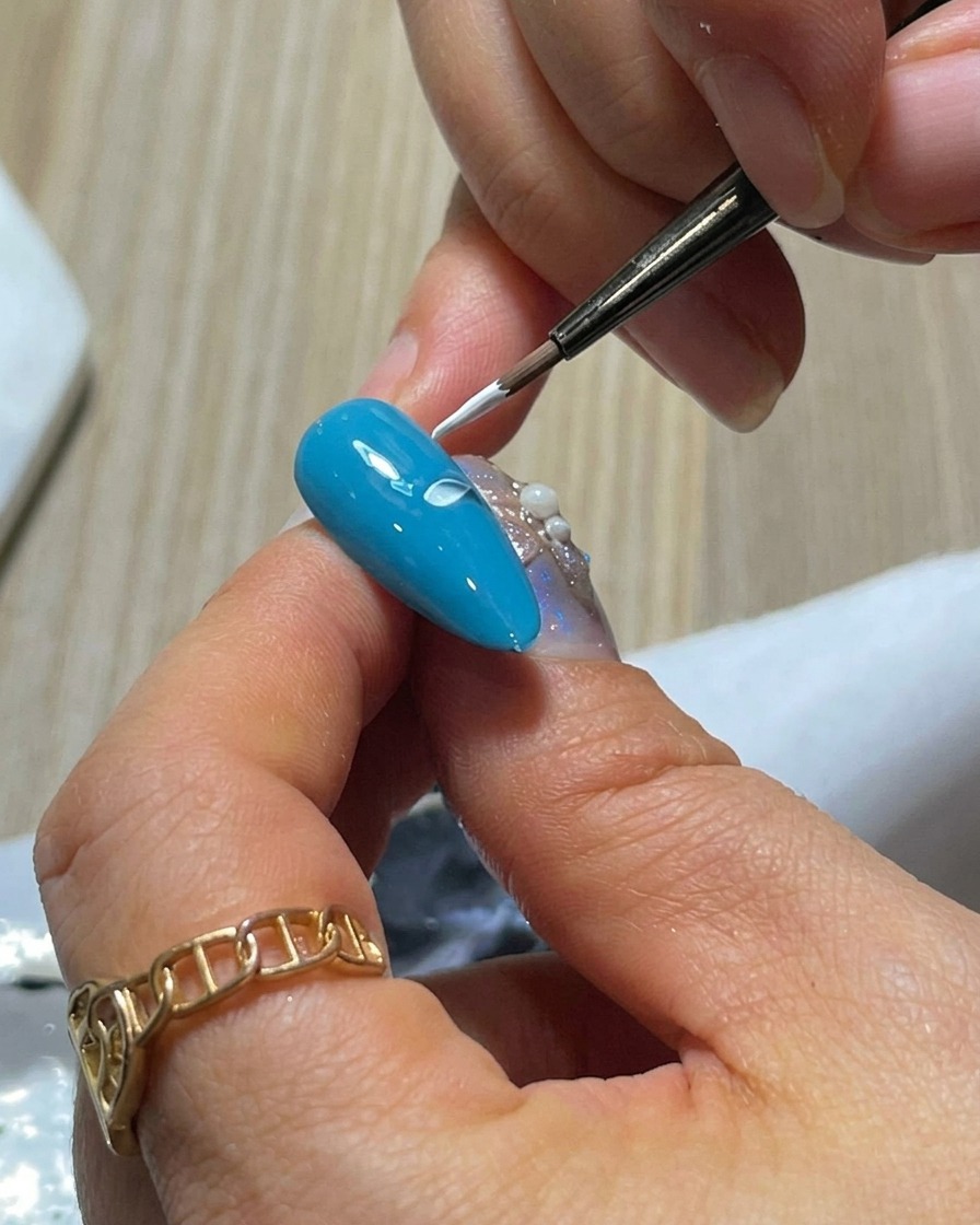 Close-up of a blue nail with two white gel petals painted side-by-side using the press-and-lift technique.