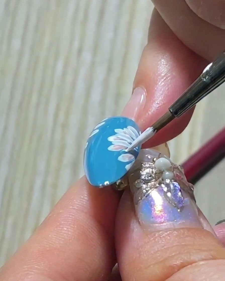 A close-up view showing the fourth petal of the upper layer being added, finishing the primary daisy petal structure.
