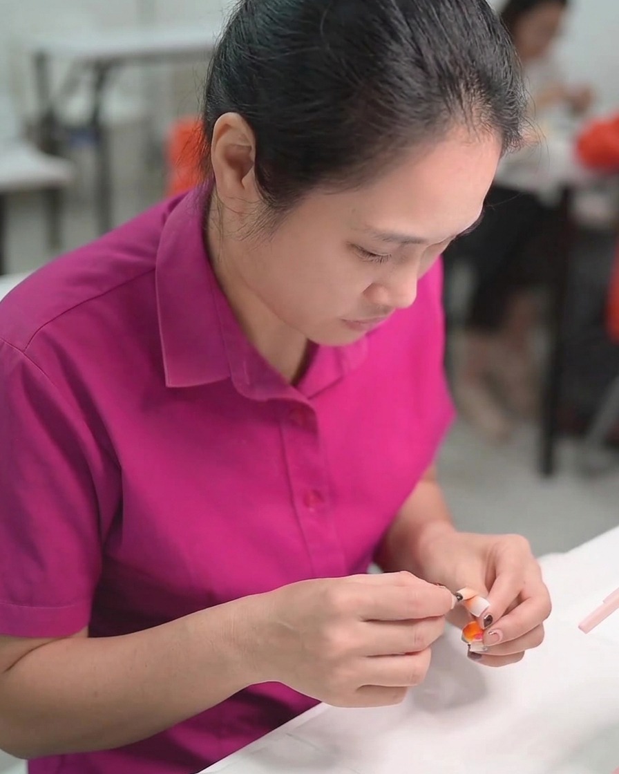 A detail liner brush applying white gel to create delicate daisy petal designs on a nail.
