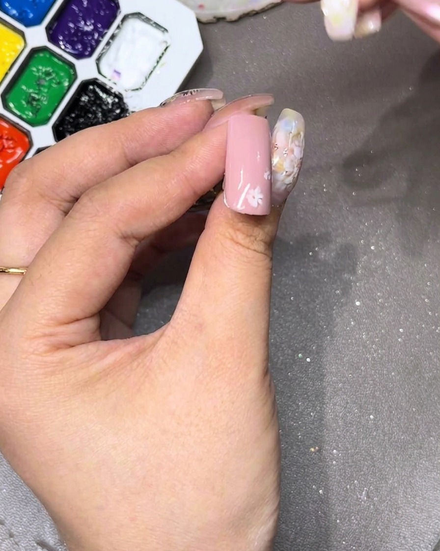 A close-up of a nail showing the initial white petal being drawn at the top.
