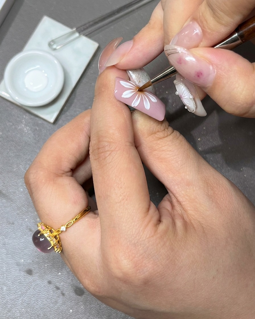 A brush applying a second layer of white gel petals over the initial flower layer to add depth.