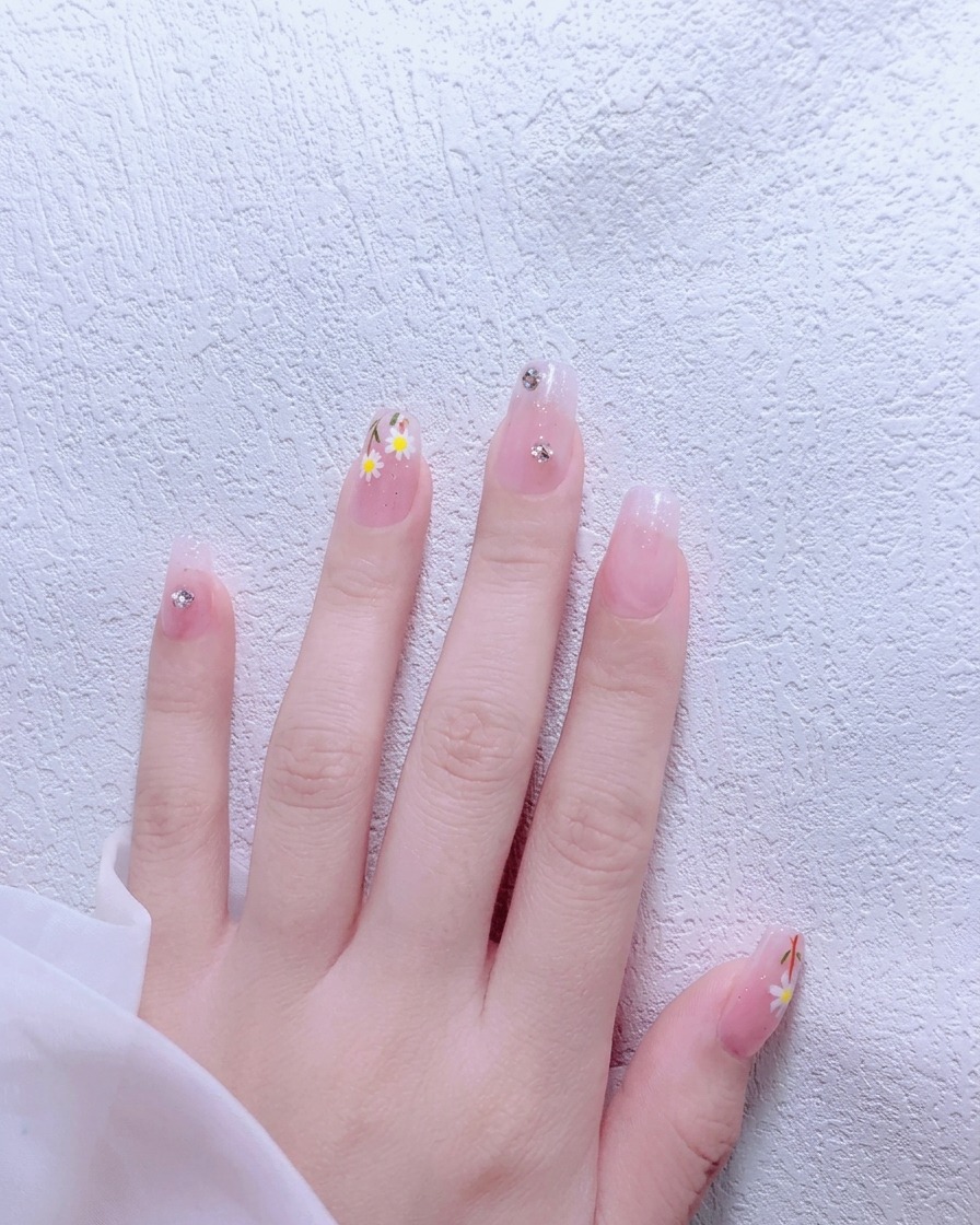 A brush applying nude pink gel polish onto a natural fingernail.