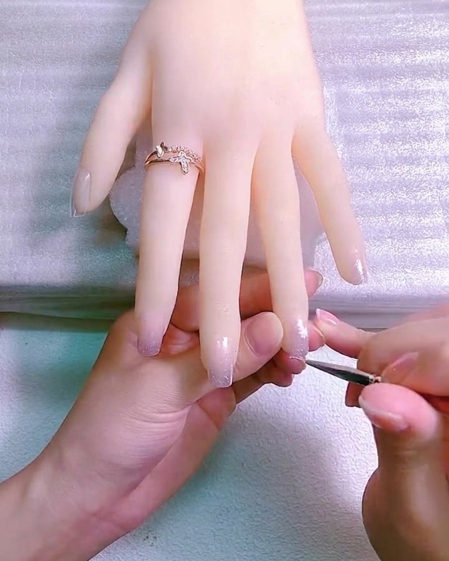 Two daisy flowers painted on the nail, one slightly larger than the other.