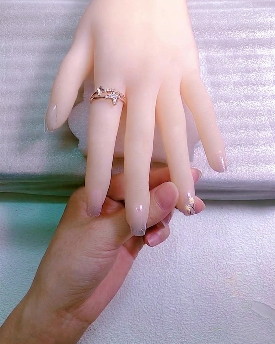 A nail artist using a tool to place a small crystal charm into a drop of adhesive gel on a fingernail.